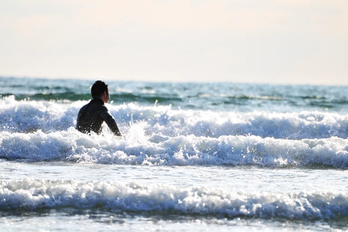 A surfer wading into the waves on the Shonan coast