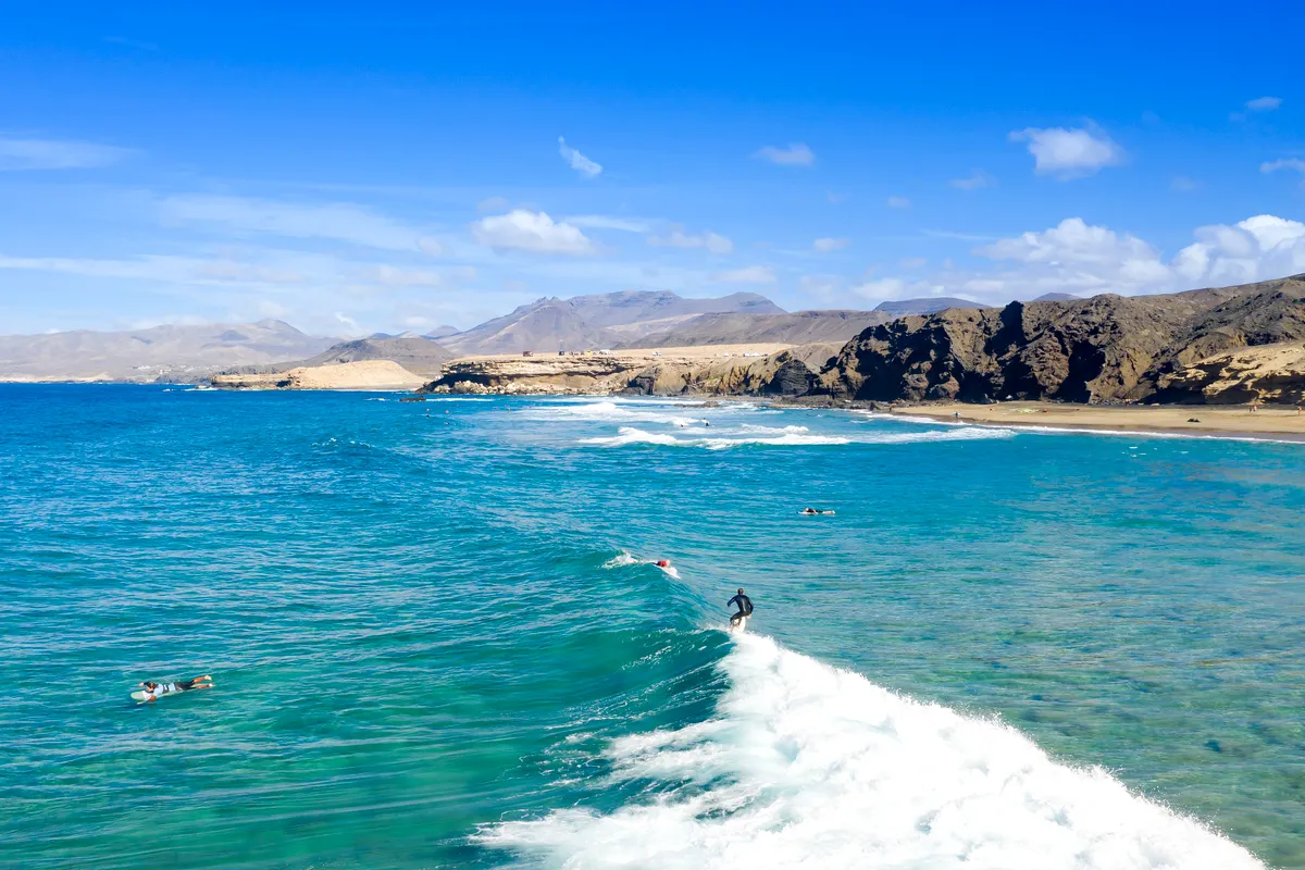 Aerial view of surfers on a turquoise wave off the coast of Fuerteventura