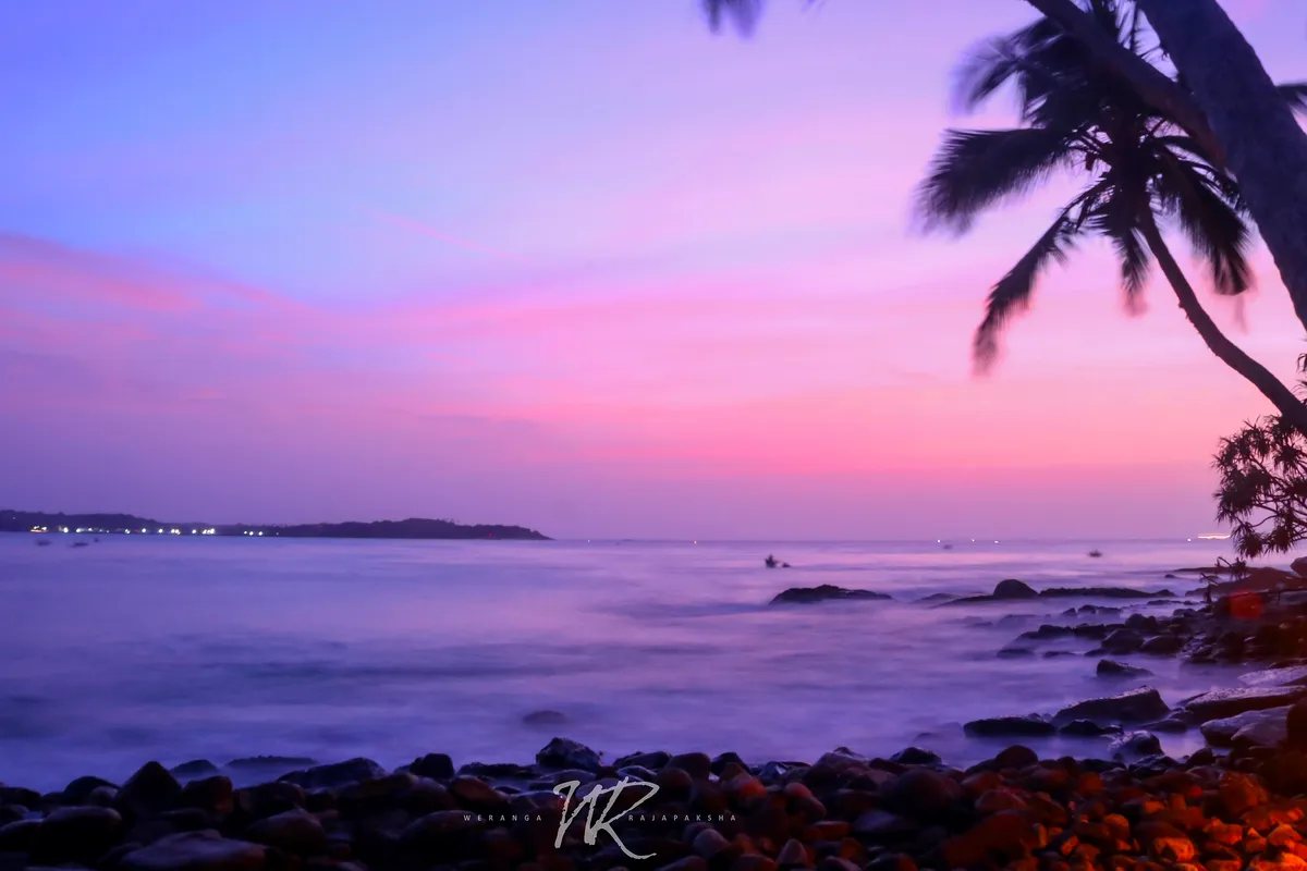 Sunrise behind a palm over Blue Beach Island at Nilwella, near Hiriketiya