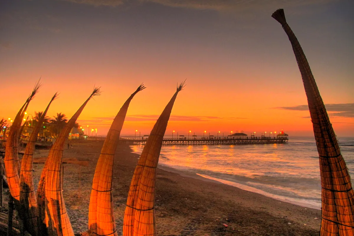 Caballitos de totora reed boats standing on the beach at Huanchaco at sunset