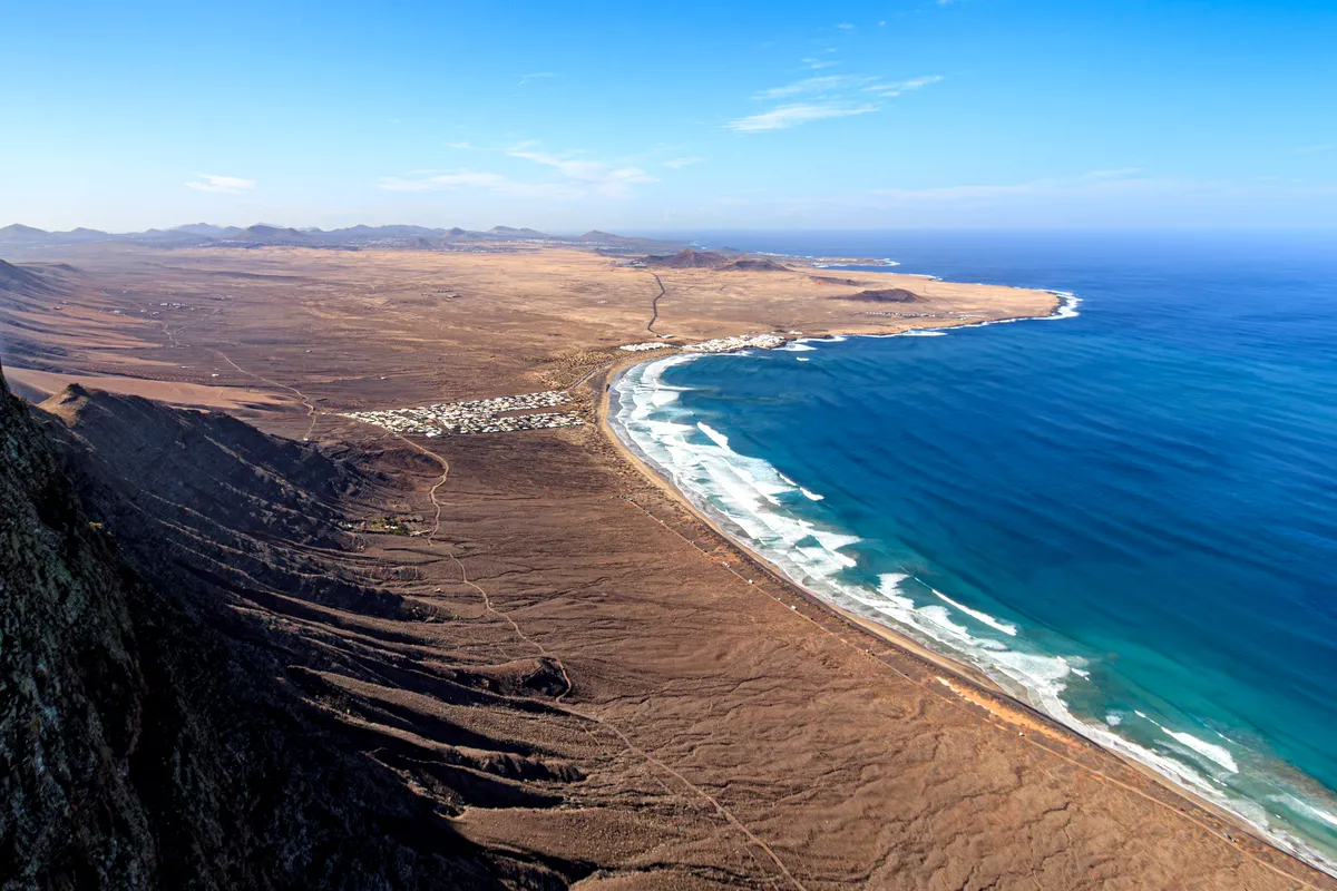 Famara beach curving below the Famara cliffs, Lanzarote