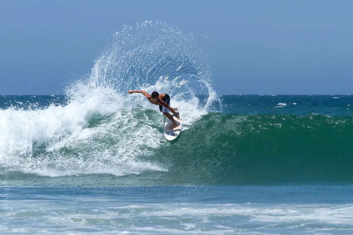 A surfer throwing spray off the top of a wave at Máncora