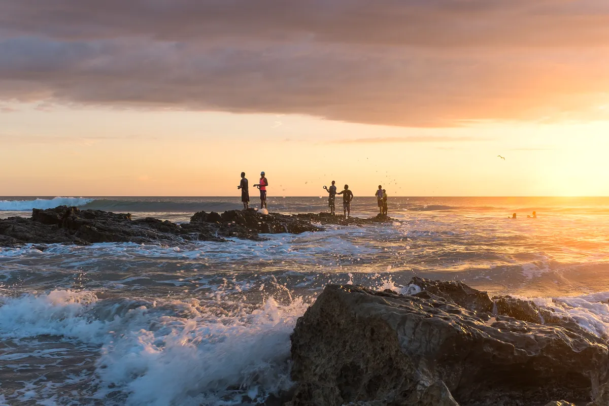 Fishermen on the rocks at sunset, Playa Santa Teresa, Costa Rica