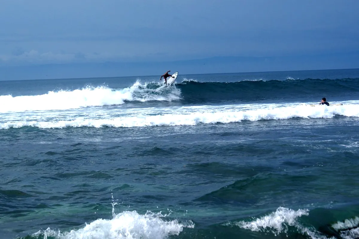 Surfers riding the reef waves at Uluwatu